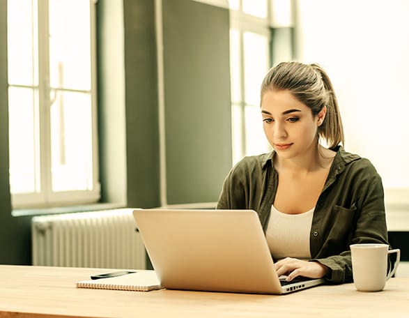 Casual young woman using laptop at home office. - Seahawk