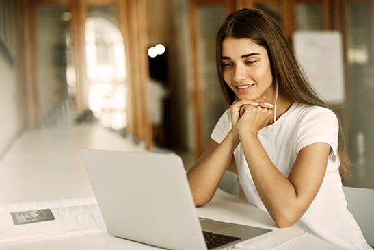 Student using a laptop computer to call parents abroad. Young woman using a notebook to listen to watch a movie. - Seahawk