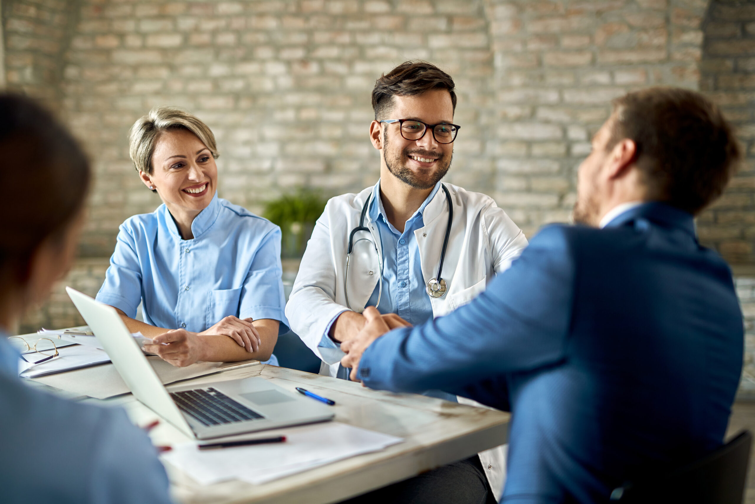 Happy doctor shaking hands with a businessman on a meeting in th - Seahawk